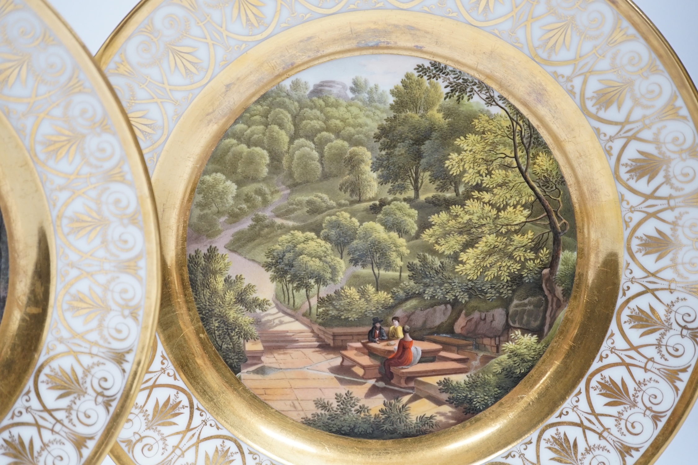 A pair of early 19th century Paris porcelain titled landscape and gilt decorated dishes, 24.5cm diameter